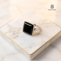 انگشتر مینیمال با نگین سنگ اونیکس مشکی مربعی برند JANA GEM روی پایه مرمری سفید